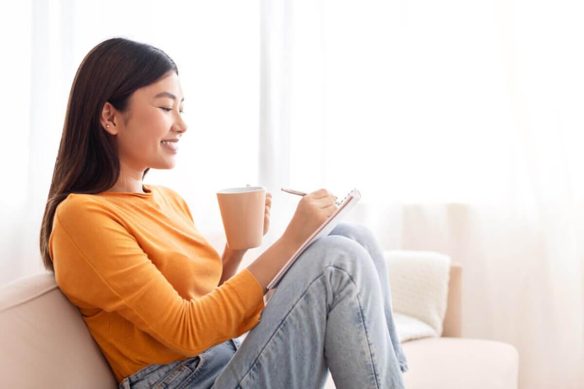 Woman sips her morning coffee and journals.