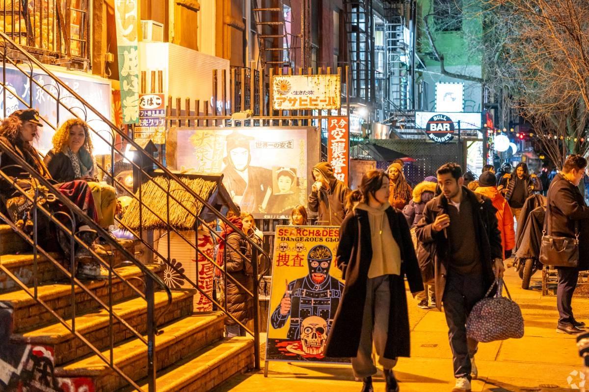 Pedestrians walk throughout the East Village at night.