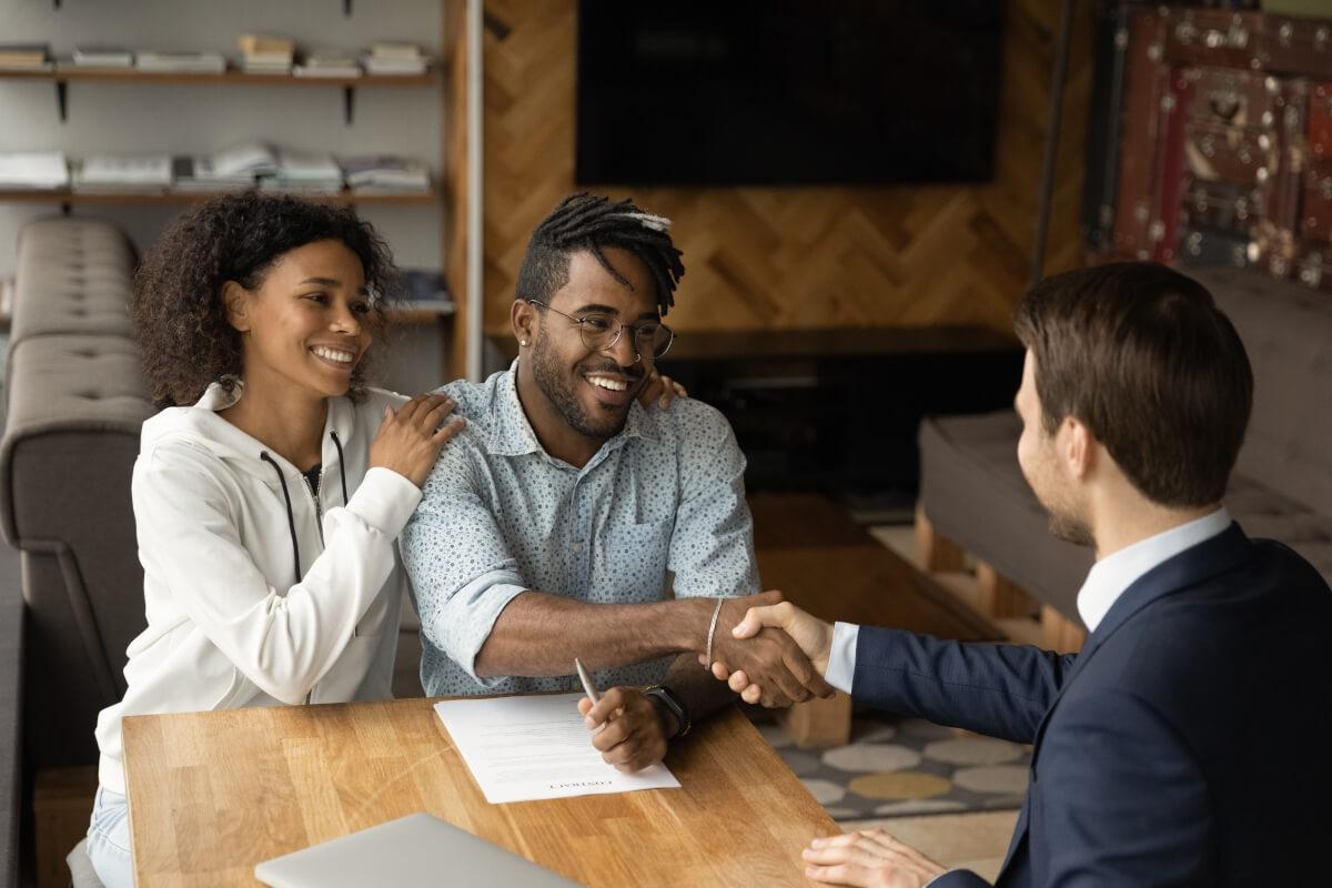 Couple shaking hands with businessman.