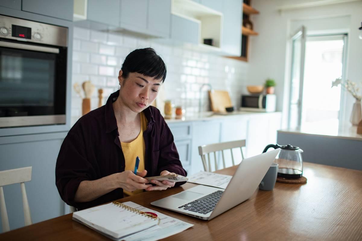 Woman calculates monthly budget in her kitchen.