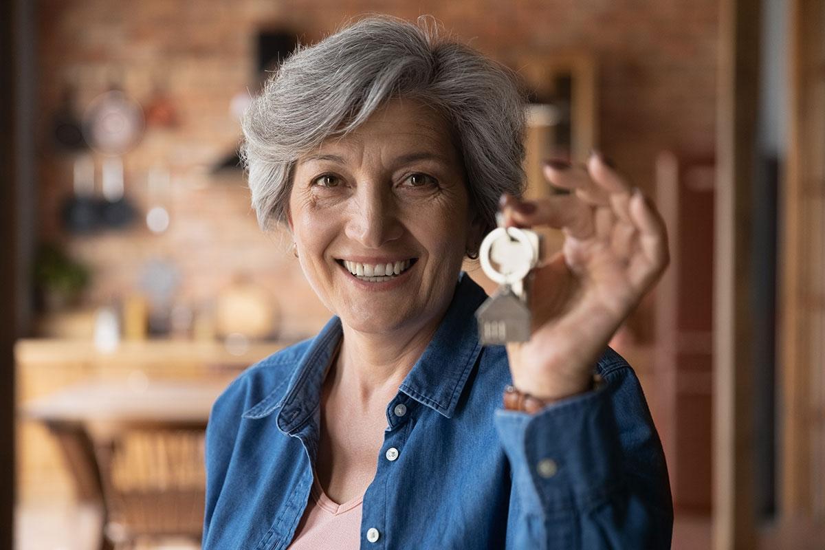 Senior lady happily holding up new apartment key.