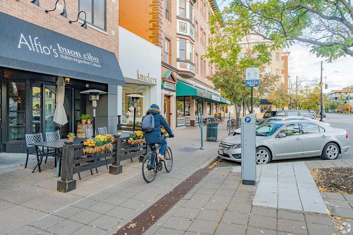 Person biking past storefronts underneath apartments in Hyde Park.