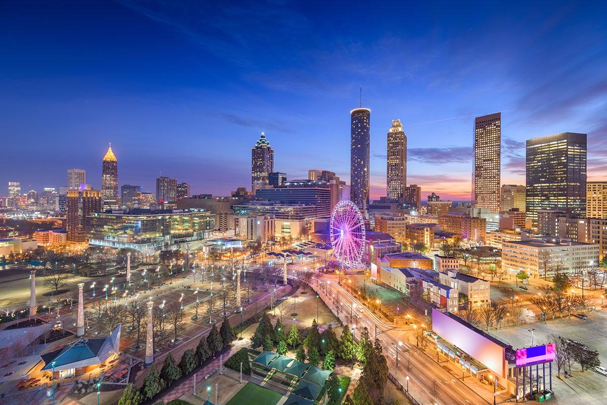 The skyscrapers and ferris wheel in Downtown Atlanta glow during the evening.