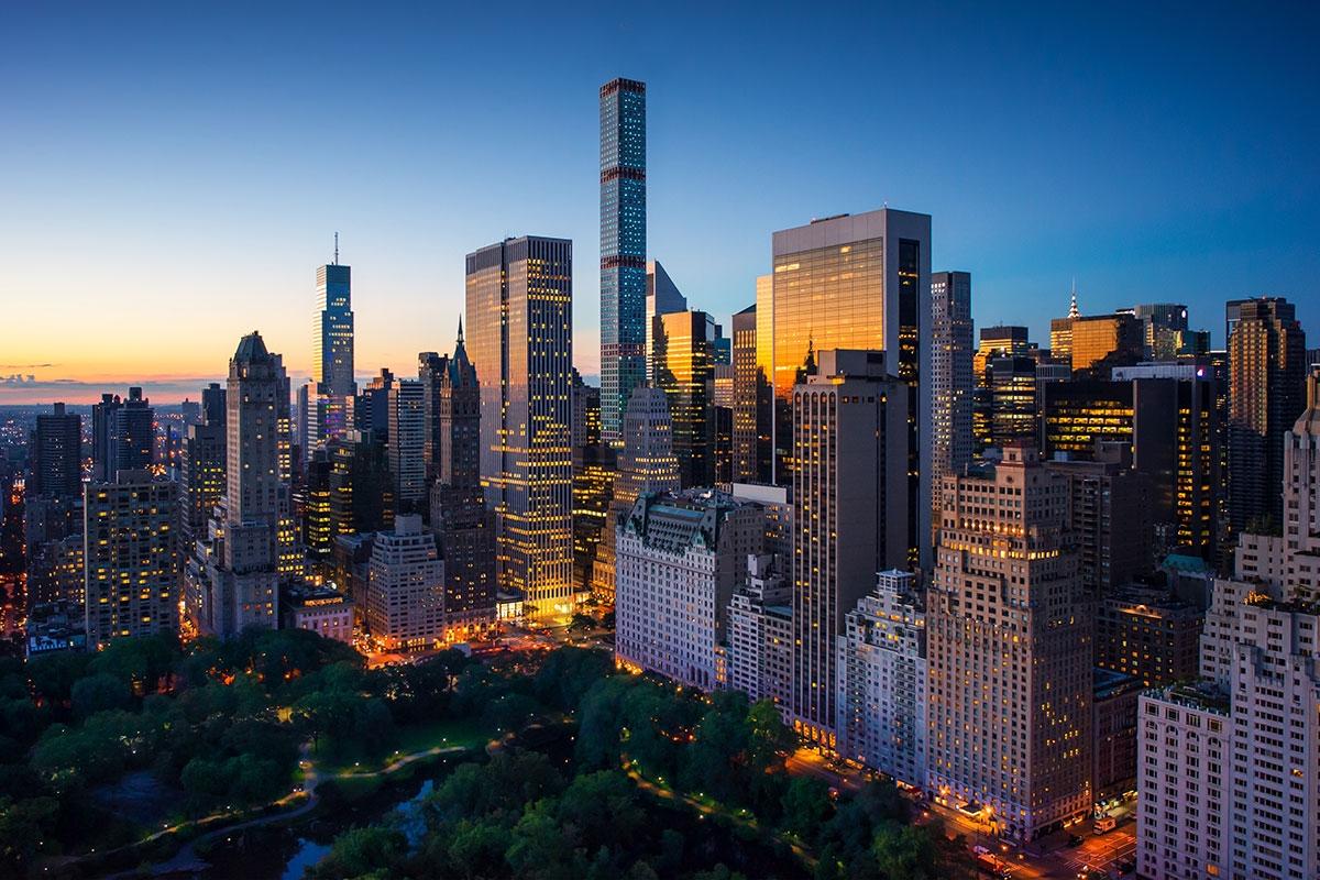 Skyscrapers rise around Central Park in New York during twilight.