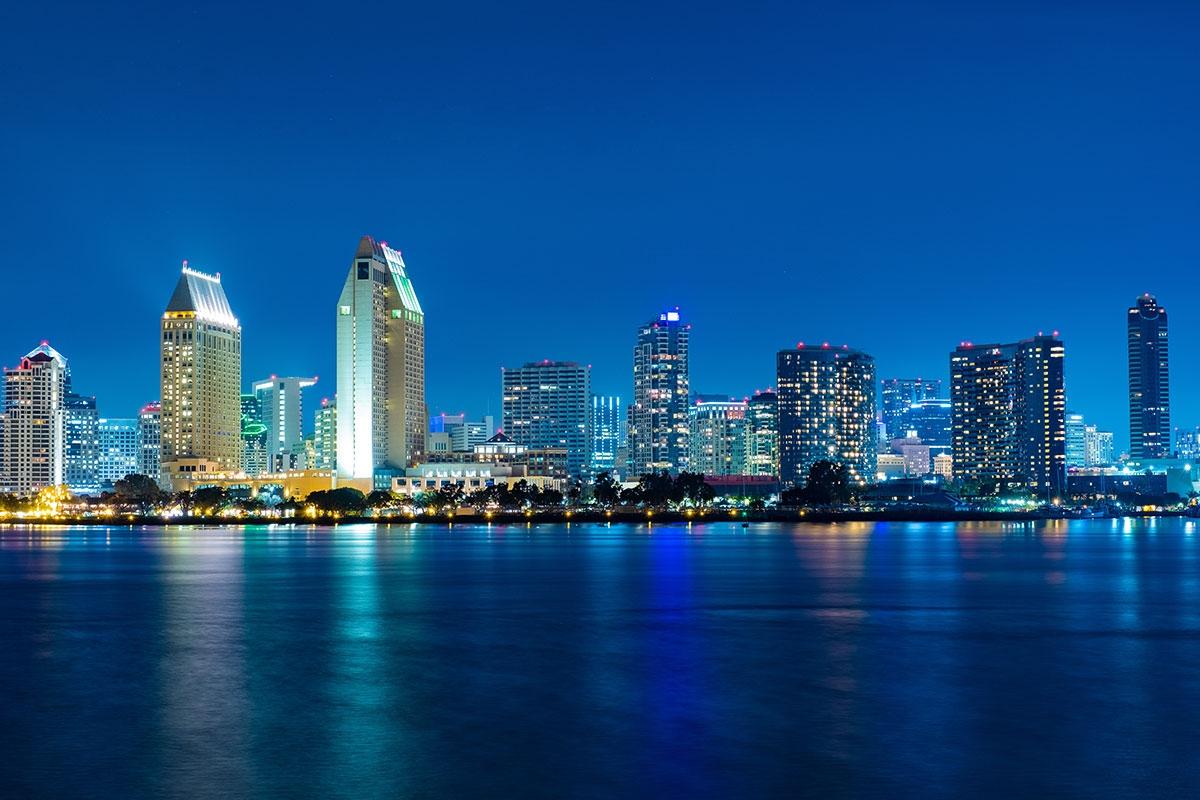 San Diego's buildings glow blue during the night that matches the water.