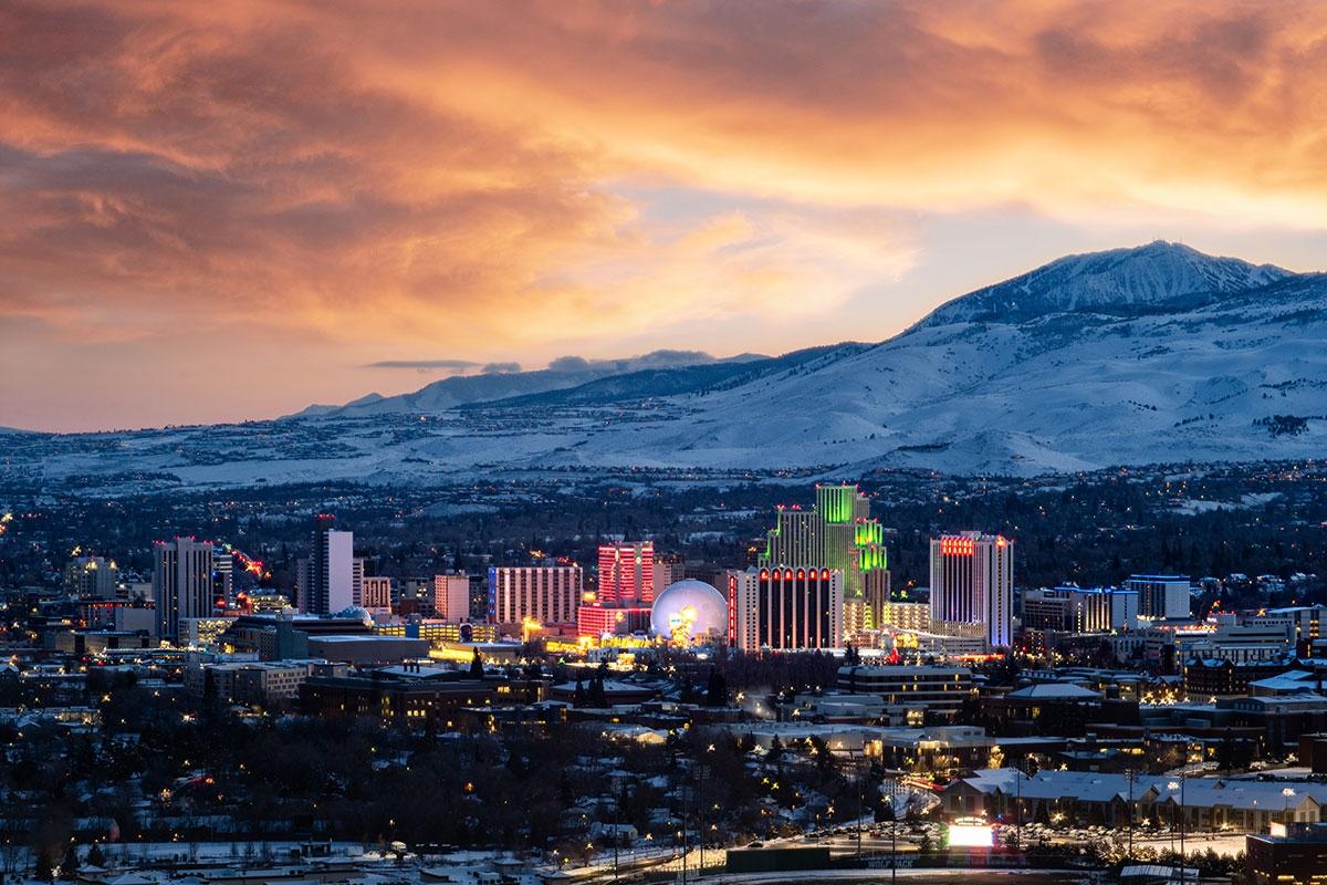 Downtown Reno's lights shine during the evening against the backdrop of the surrounding mountains..