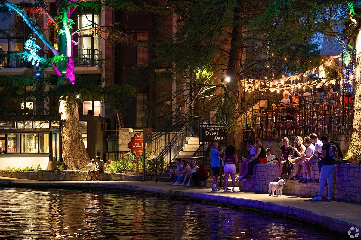 People sit on a wall and chill with their dog on the San Antonio River Walk.