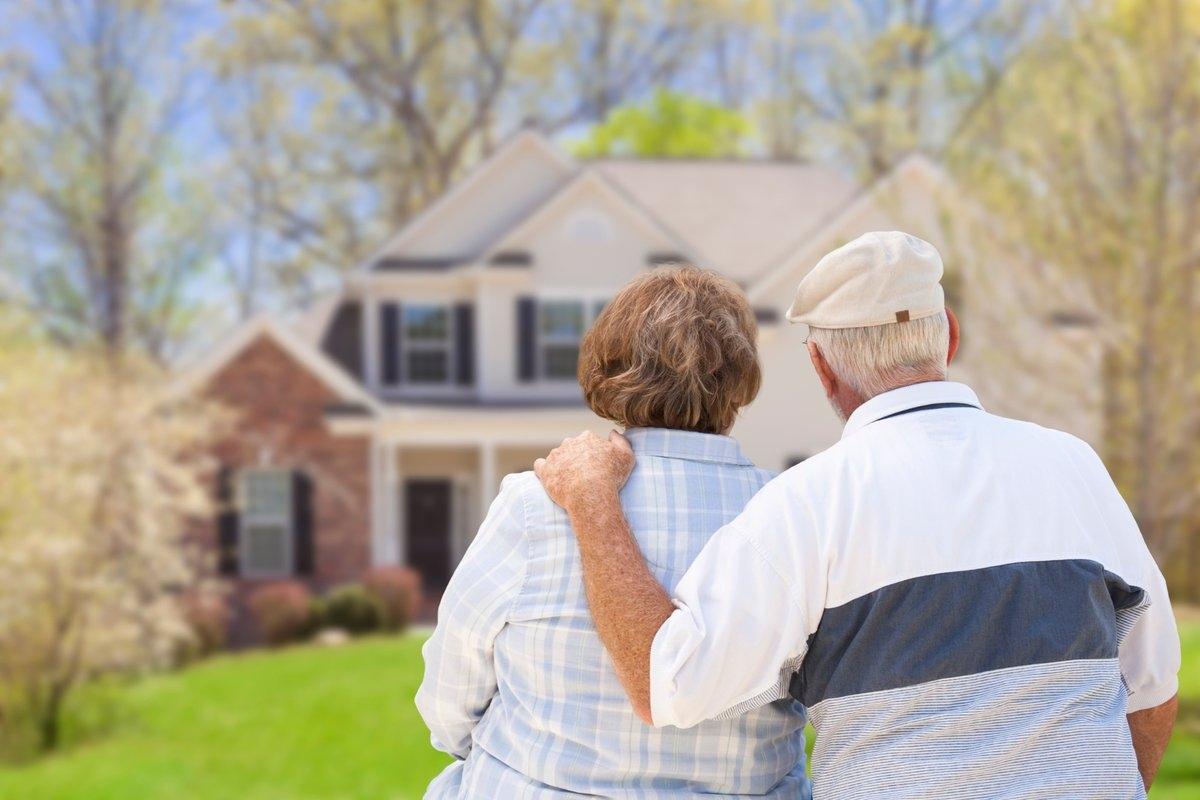 A senior couple looking at their large home from the outside
