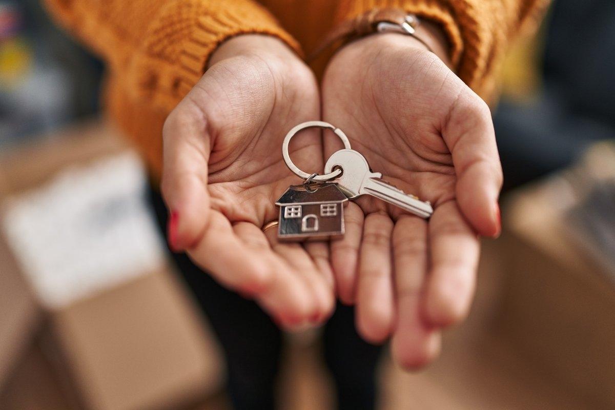 Open hands holding a house key 