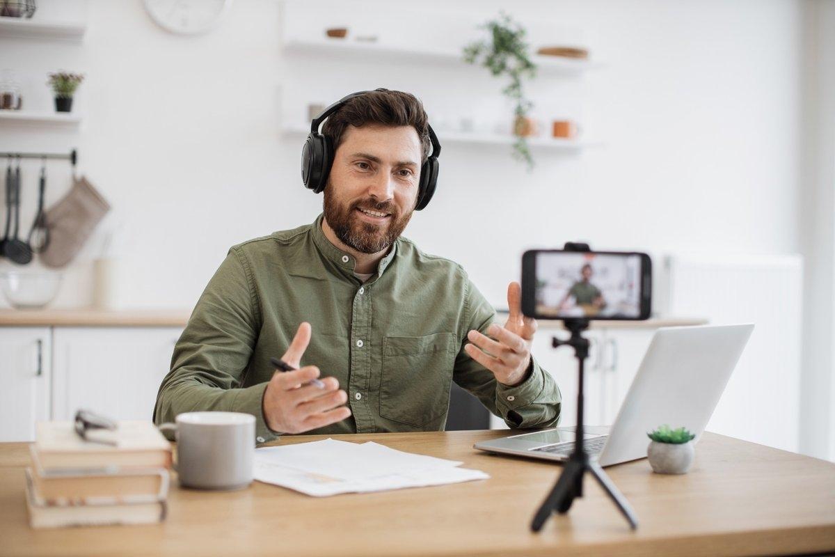 Influencer with a tripod camera and headphones sitting at a table