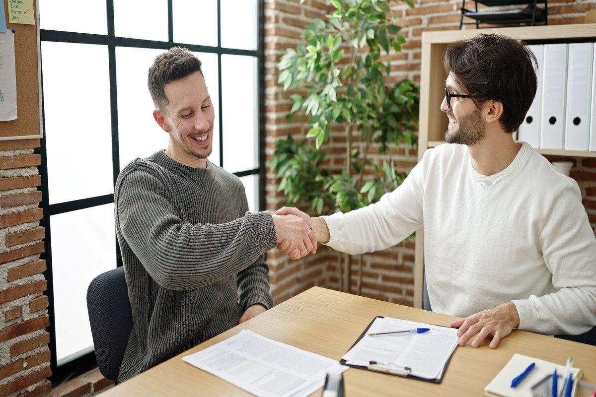 Two men shaking hands after signing paperwork