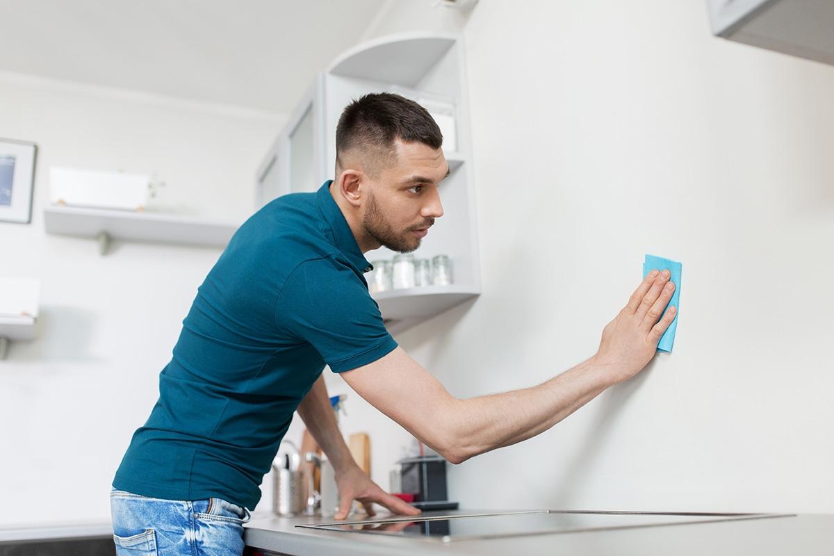 Man cleaning the backsplash in a kitchen.