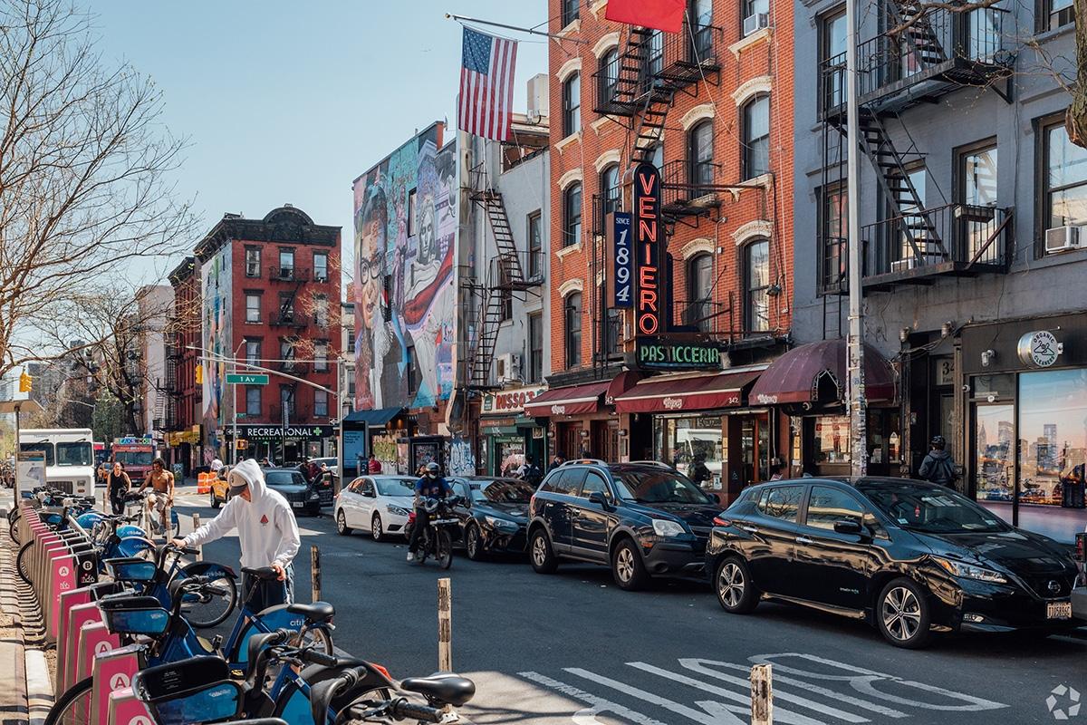 A man getting out a Citi Bike in East Village in front of well-known restaurants.