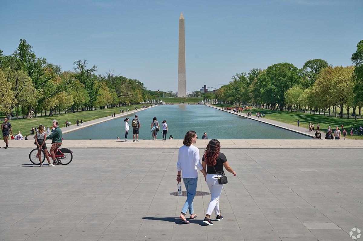 People stroll in front of the Reflecting Pool with the Lincoln Memorial in the background.