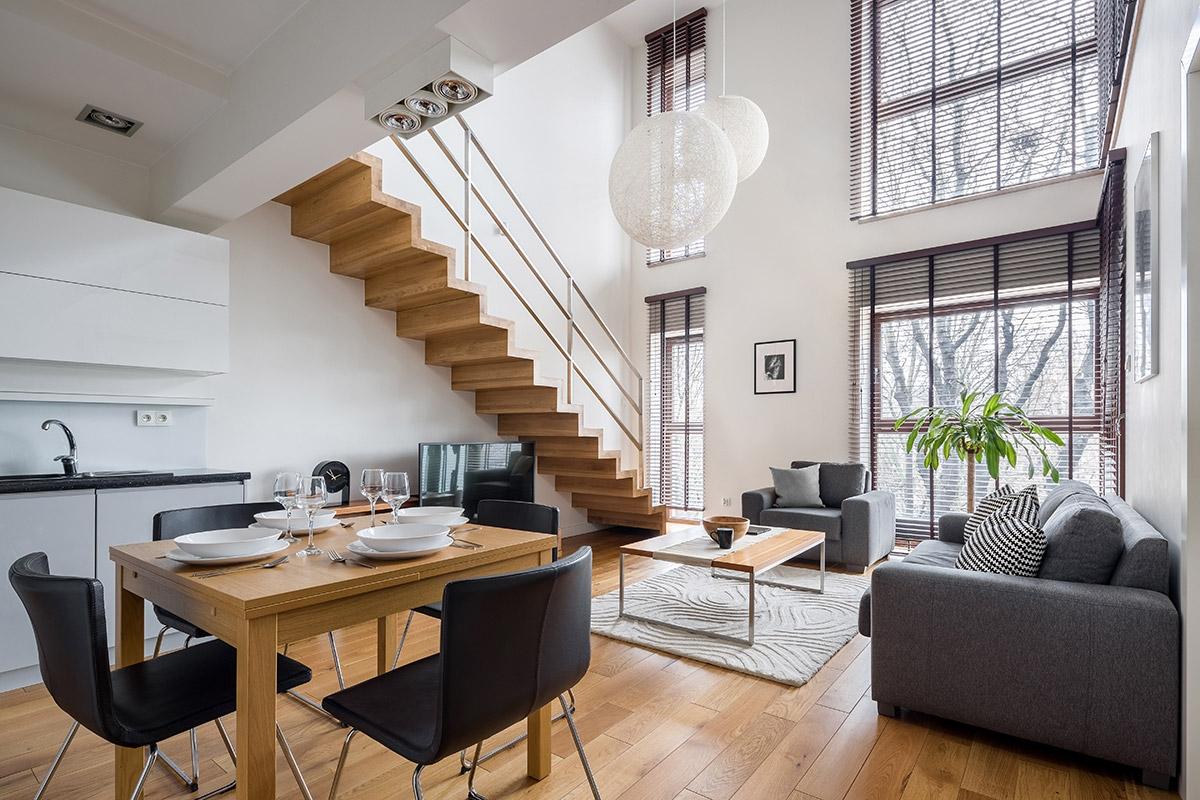 Open living room with lots of light and stairs leading up to the loft.