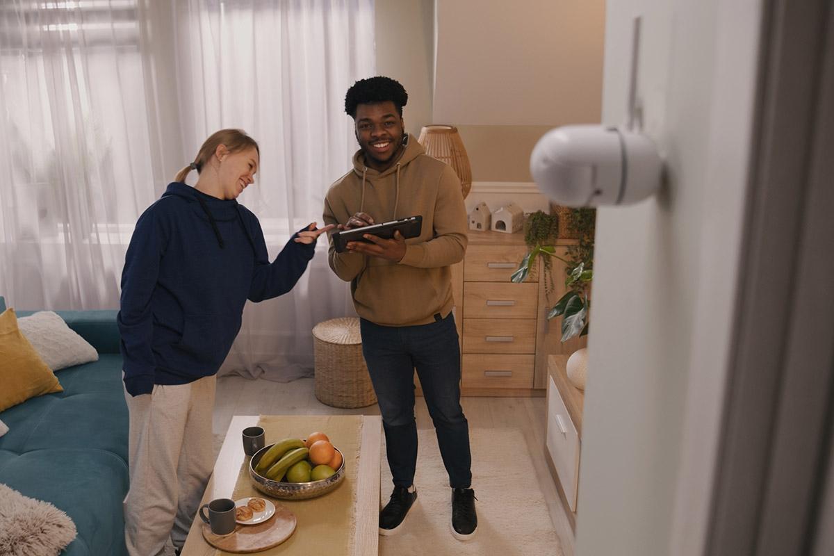 Man and woman setting up security camera in apartment.
