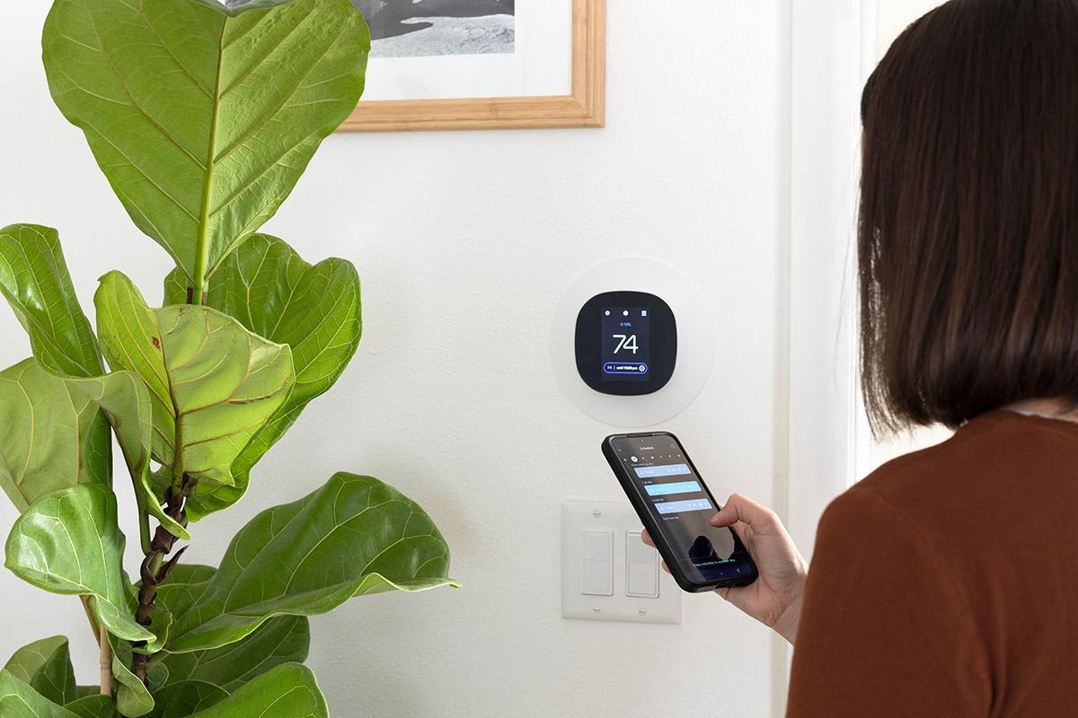 Woman adjusting the thermostat via her phone.
