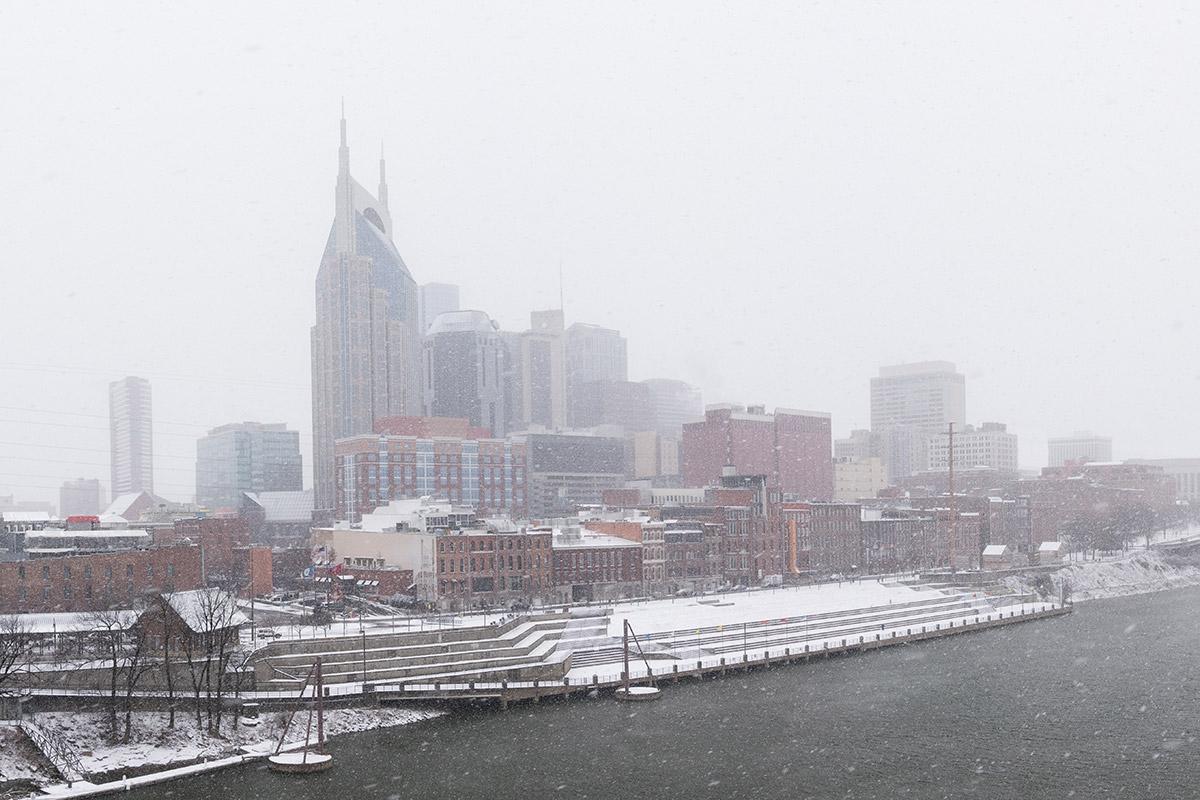 The Nashville skyline and riverfront covered in snow during the winter.