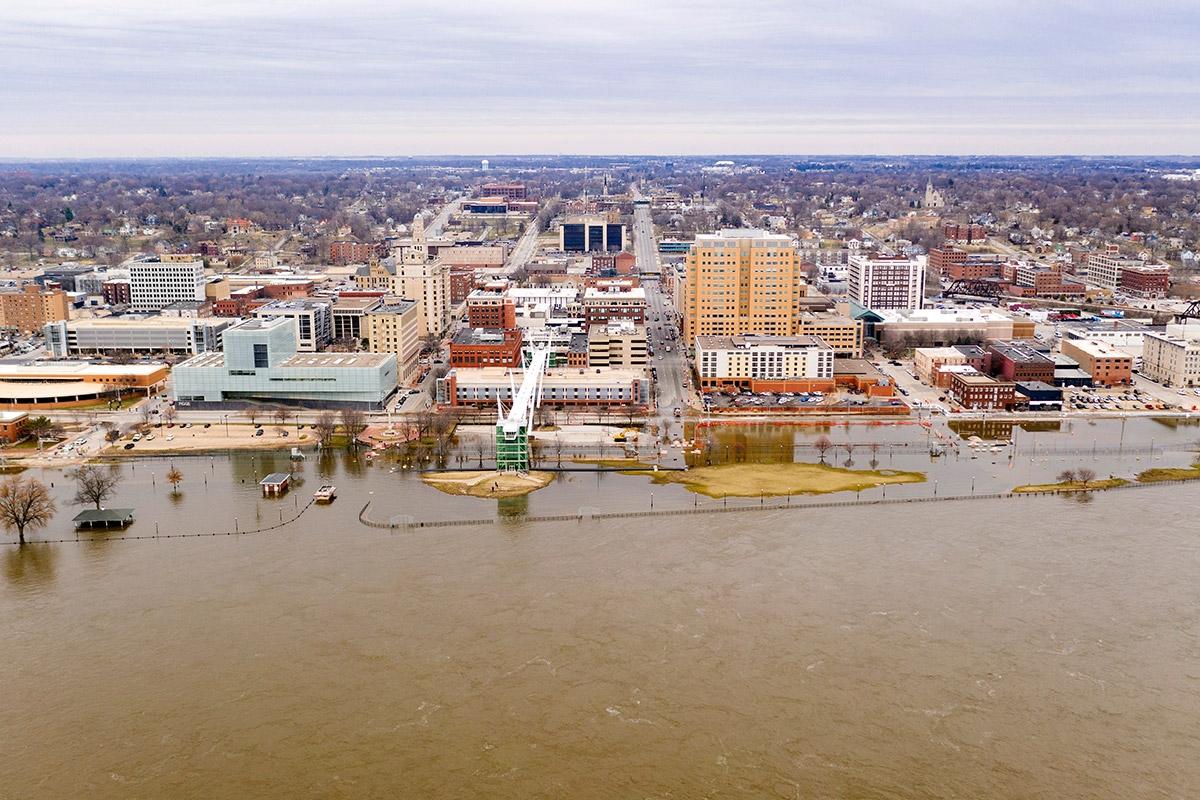 A river flooding the riverbank of a downtown.