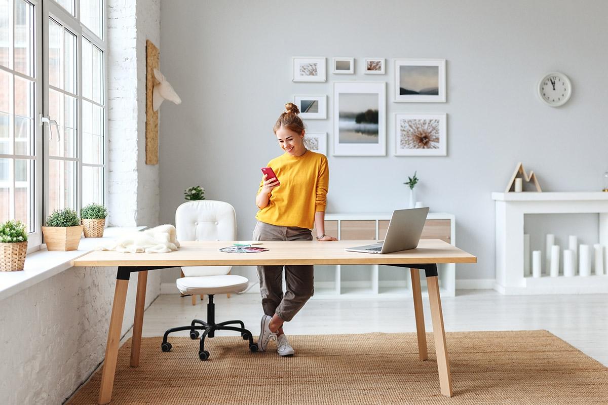 Woman standing at desk in apartment living room.