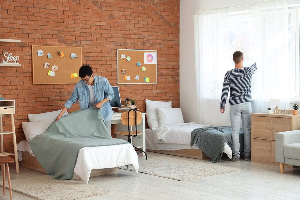 Two men setting up their shared bedroom.