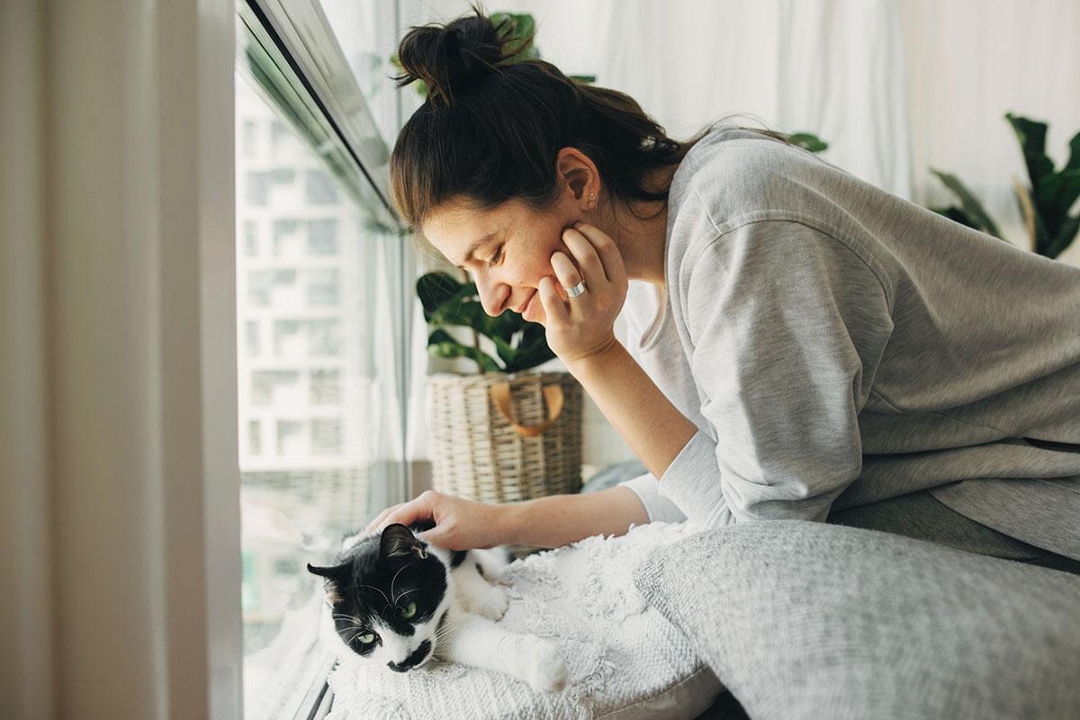 Girl in her apartment petting her cat.