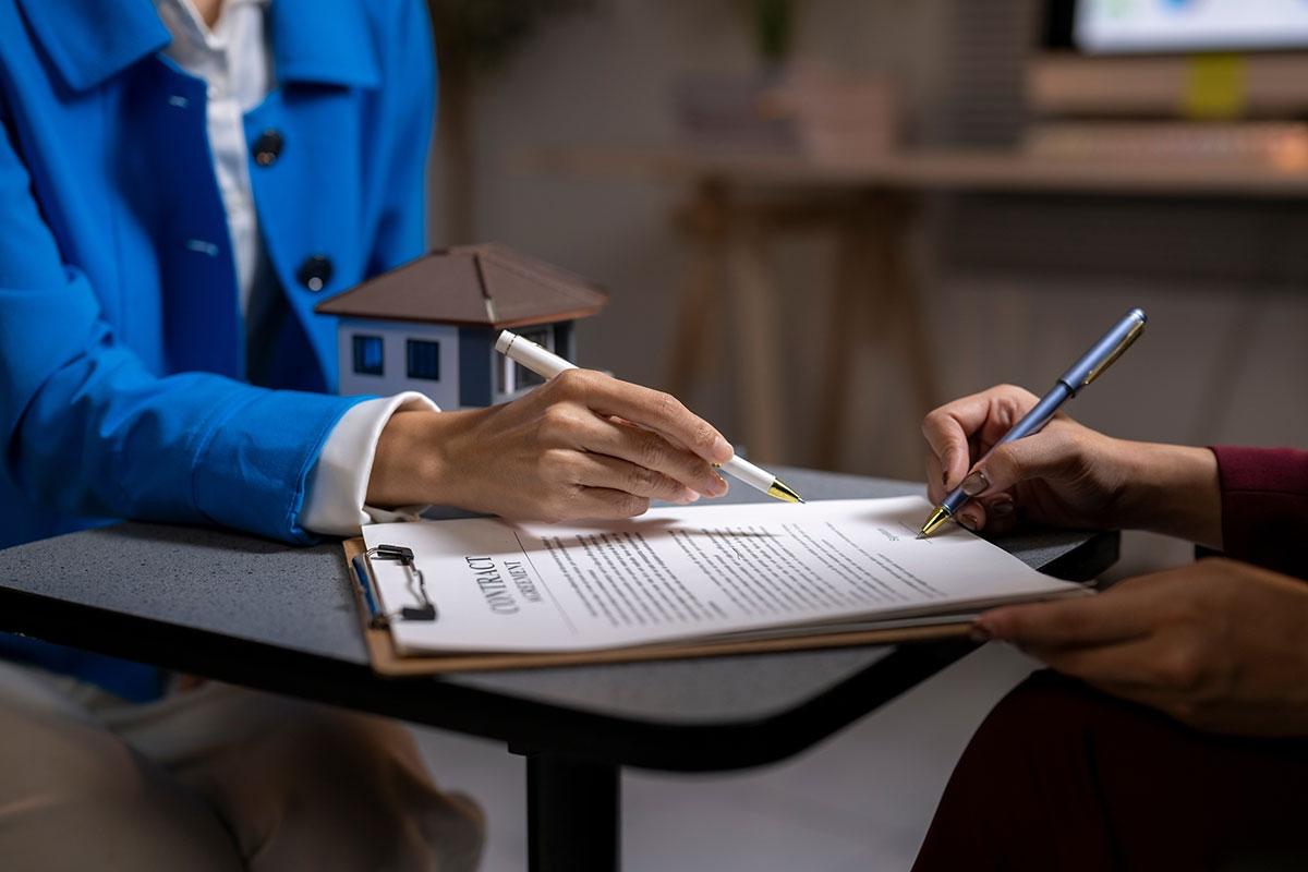 A leasing agent showing the renter where to sign the lease.
