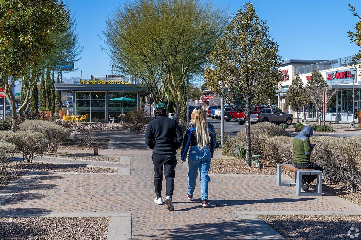 A pair of people walk on a brick sidewalk past Stonehaven's shops and restaurants.