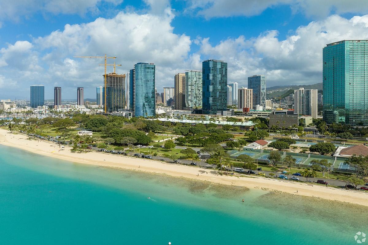 Glass high-rises sit back from the scenic beaches of Honolulu, separated by parks and recreation spaces.