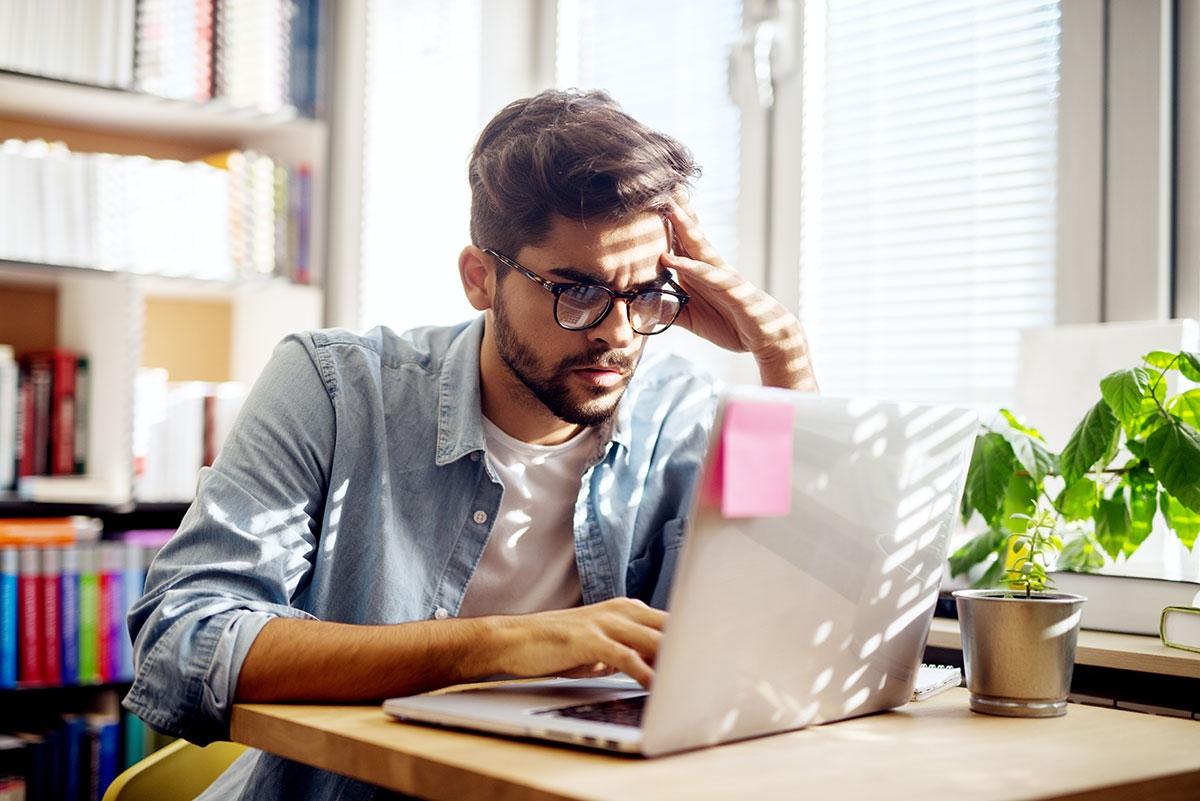 Man is looking at laptop and stressed.