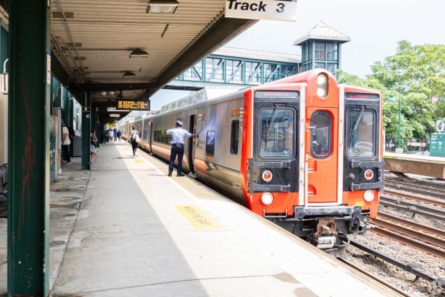 Conductor waving as train sits in station.