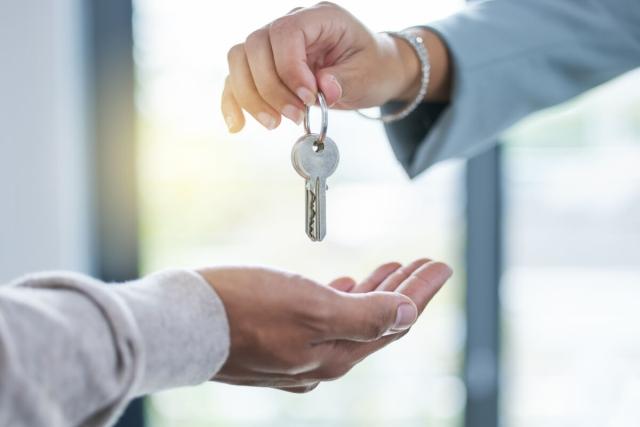 Photo of a person handing keys to another person.