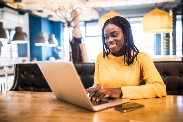 A young woman searches for an apartment online while sitting at a coffee shop.