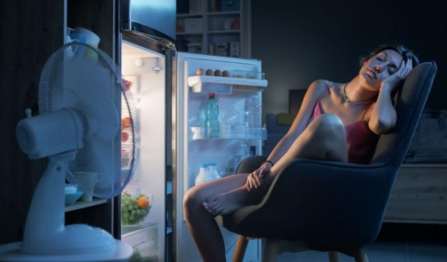 Renter trying to get cool in hot apartment by sitting in front of the refrigerator.