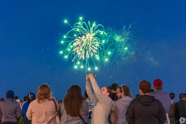 Crowd watches a vibrant green firework explode against the night sky at Navy Pier.
