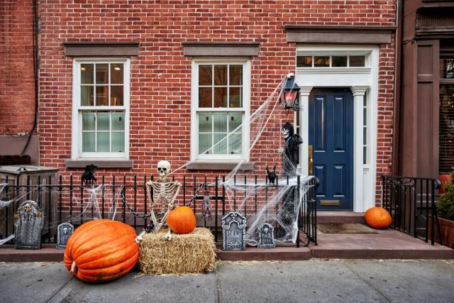 Skeletons, pumpkins, cobwebs, and headstones decorate a front door for Halloween.