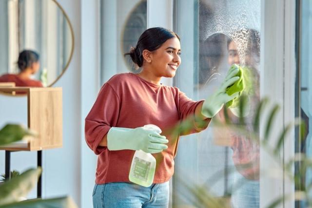 Woman wipes her apartment windows.