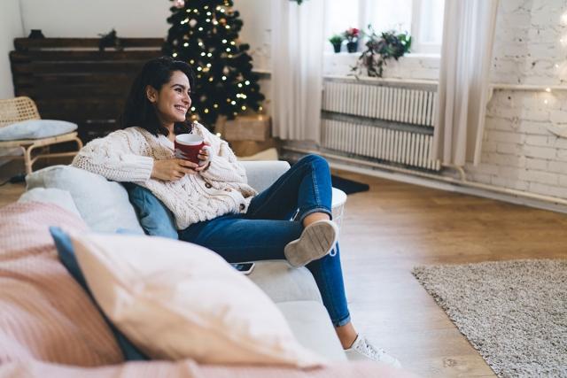 Woman holding mug in cozy apartment during christmastime.