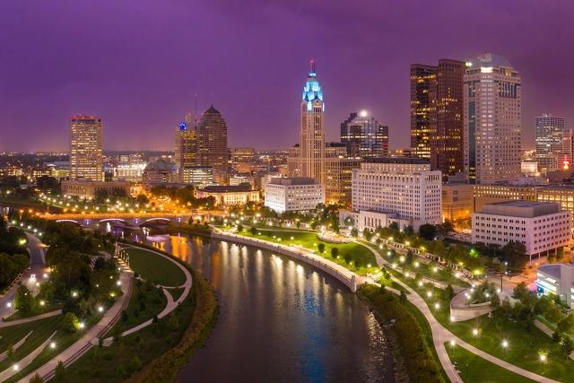 The buildings along the Scioto River shine with light during the late evening.