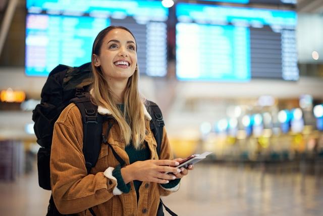 Woman holding her passport smiling in an airport.