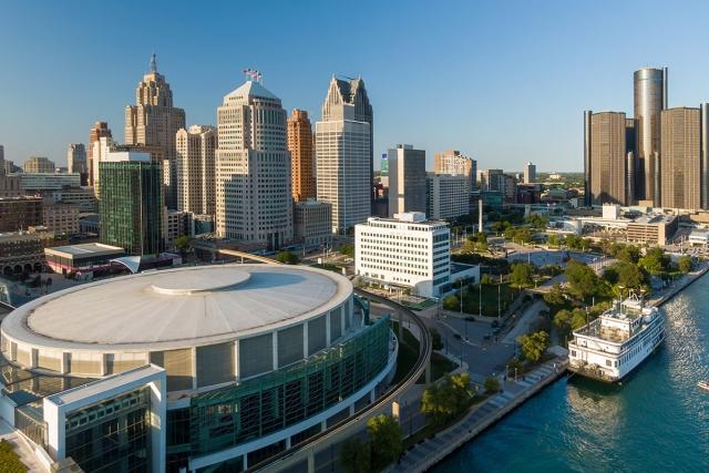 The riverfront of Detroit contains venues, a riverboat, and many high-rise buildings.