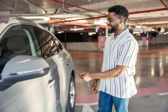 A man inside a parking garage unlocks the door to his car.
