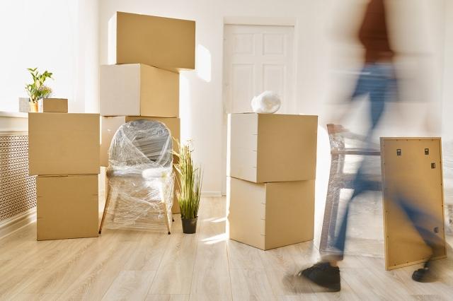 A blur of a renter moves past moving boxes and furniture in an apartment.