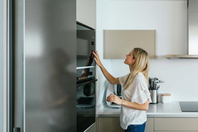 A woman adjusts the settings on her microwave in her apartment.