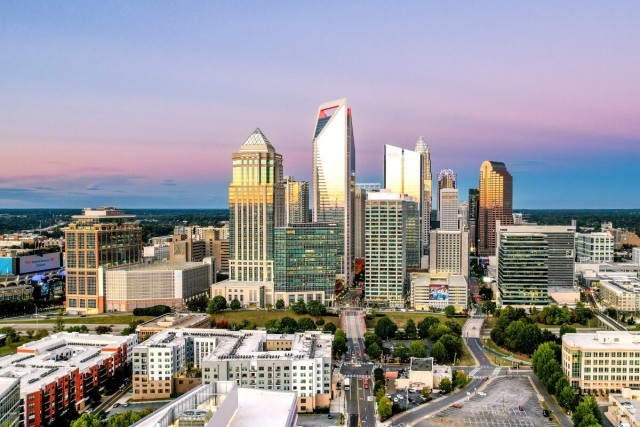The Charlotte, NC, skyline in front of a pink and purple sunset.