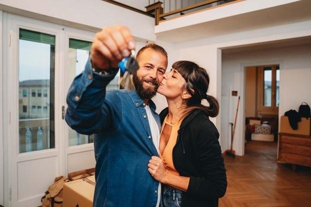 A couple embraces while showing off the keys inside their new apartment.