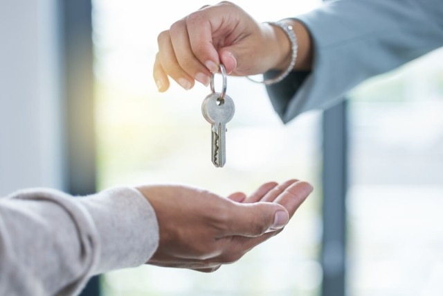 Photo of a person handing keys to another person.