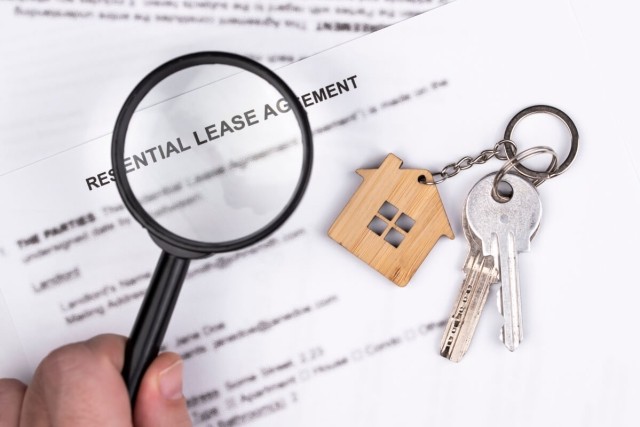 Reading a lease agreement with a magnifying glass