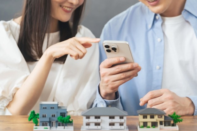 Two people searching for a rental on their phone as rental models sit in front of them.