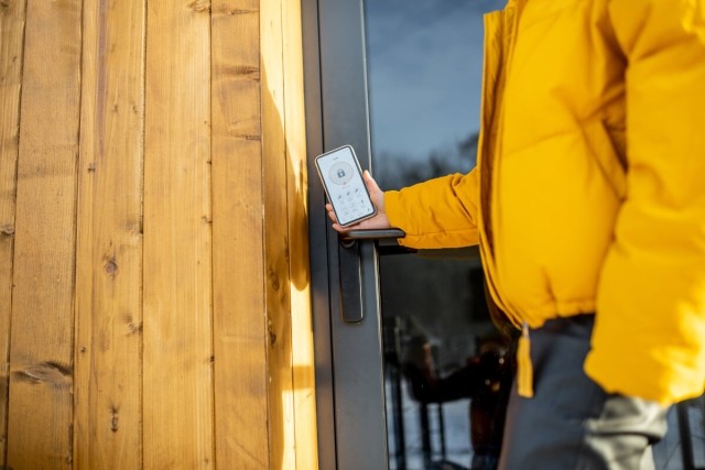 A person unlocks the door of a rental through a mobile app.